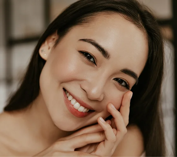A portrait of a woman with her hair pulled back and neutral makeup, looking directly at the camera with a calm expression against a soft-focus indoor background. - In Los Angeles, CA